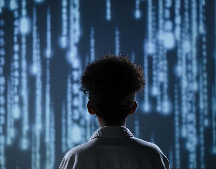 A young boy viewing a digital screen with data streams, symbolizing technology interaction.